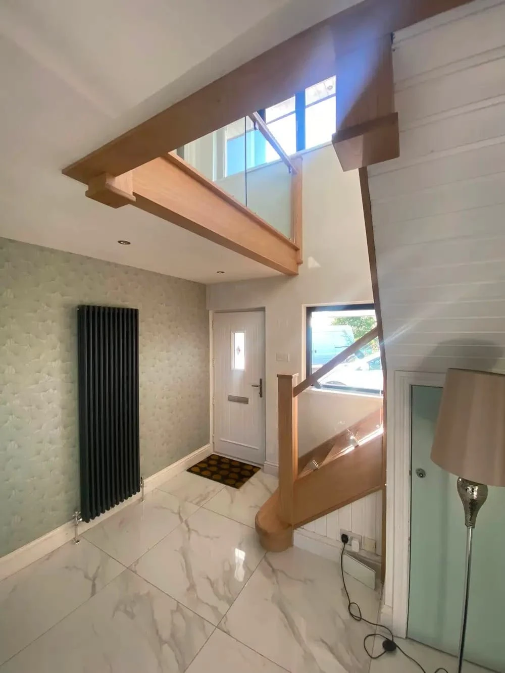Entrance hall with oak and glass staircase rising over the front door, oak gallery landing above
