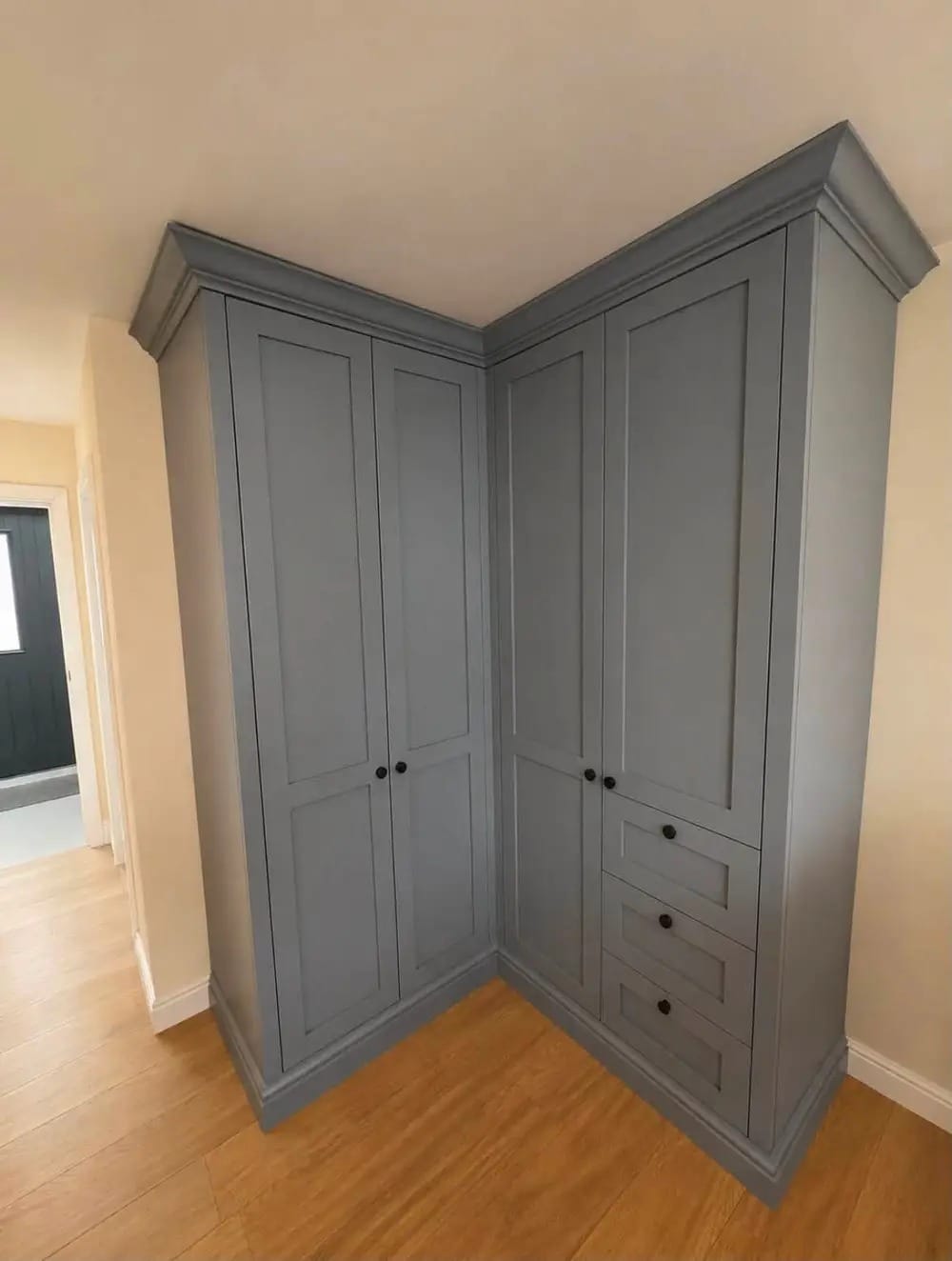 Grey shaker-style corner wardrobe with panelled doors, drawers and moulded cornice